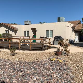 A house with a deck and gravel landscaping in the yard under a clear blue sky.