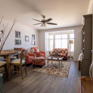 A cozy living room with floral-patterned furniture and ample natural light.