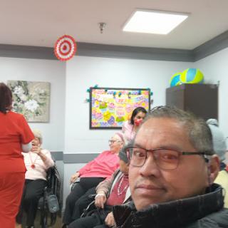 A lively social gathering at a community center for the elderly, with caregivers engaged in activities.