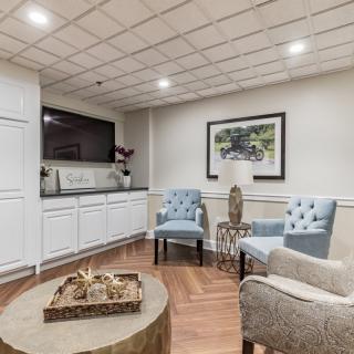 A cozy and modern seating area with elegant armchairs, a round coffee table, and stylish artwork on the wall.