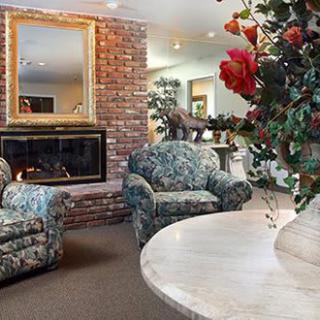 A cozy living room with floral armchairs and a brick fireplace.