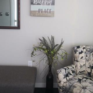 A cozy corner of a living room with a floral armchair, decorative plant, and wall art bringing a sense of peace.
