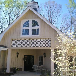 A quaint church building with a peaked roof, surrounded by budding trees in spring.