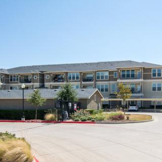 A modern residential apartment building with a spacious parking area on a clear day.
