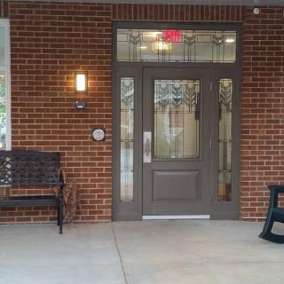 An inviting entrance with a glass door, brick walls, and seating.