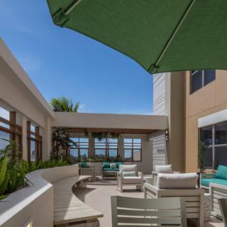 A sunny outdoor patio with seating and an umbrella.