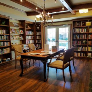 A warm and inviting library featuring wooden shelves filled with books, elegant lighting, and a comfortable reading area.