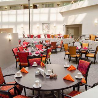 A bright and modern dining area with multiple tables and colorful chairs.