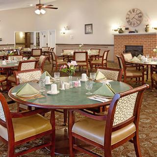 A cozy dining room setup with neatly arranged tables and chairs, featuring a warm ambiance and a fireplace.