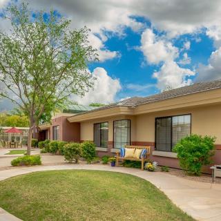 A lovely suburban home with a well-maintained garden and outdoor seating under a cloudy sky.