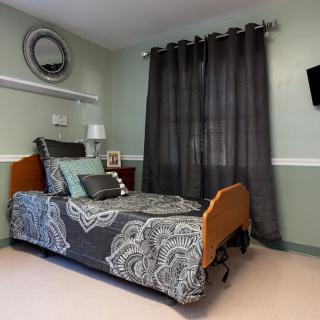 A cozy bedroom with a single bed, dark curtains, and modern decor.