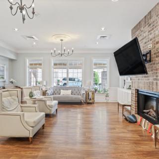 A spacious and elegantly designed living room with modern furnishings, a fireplace, and a large television.
