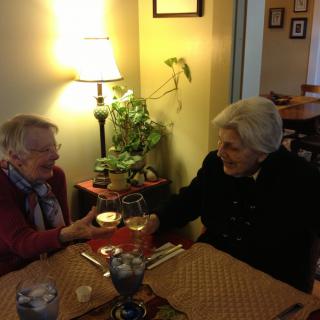 Two elderly women enjoying a conversation over a meal indoors.