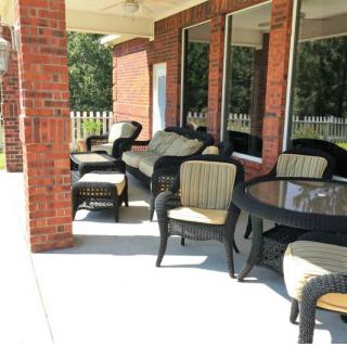 A patio with outdoor furniture including chairs and a table against a brick wall.