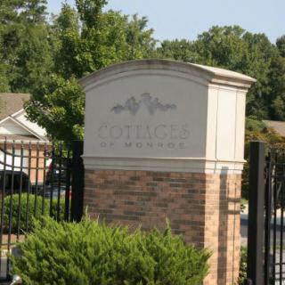 Entrance sign of a gated residential community with brick and greenery.