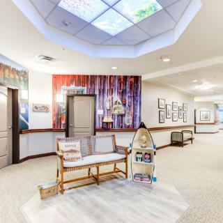 A bright and welcoming hallway featuring a cozy seating area with decorative elements and artwork on the walls.