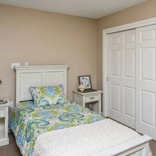 A tidy bedroom with a single bed and floral bedding, featuring a nightstand and a closet with sliding doors.