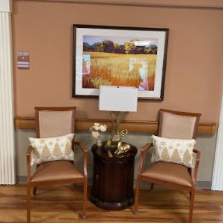 A cozy seating arrangement featuring two chairs, a lamp, and decorative artwork on the wall.