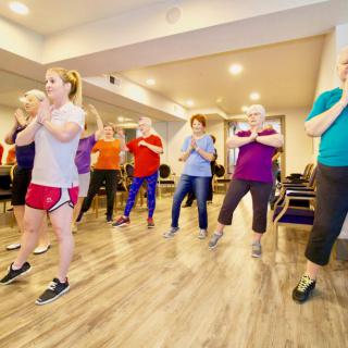 A group of people participating in an indoor fitness or yoga class.