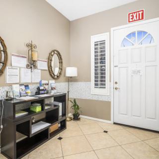 A tidy entryway of an office space with a door, shelves, and decor.