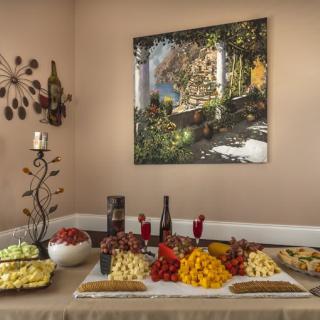 A beautifully arranged table with a selection of fruits, cheeses, and wine in an elegantly decorated room.