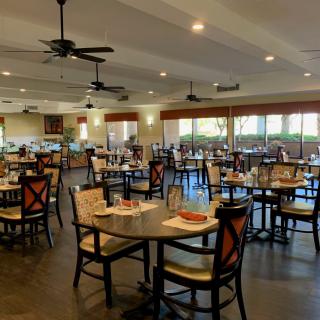 An empty restaurant dining area with neatly arranged tables and chairs.