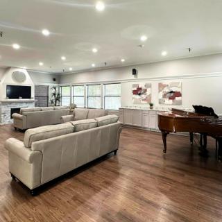 A spacious and modern living room featuring a grand piano, comfortable sofas, a fireplace, and contemporary artwork.