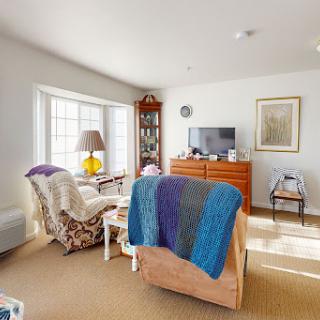A cozy living room filled with natural light, featuring comfortable seating and homey decor.