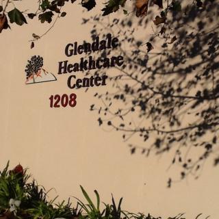 Exterior view of the Glendale Healthcare Center sign partially covered by tree shadows.