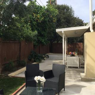 A cozy backyard patio with wicker furniture surrounded by lush greenery.