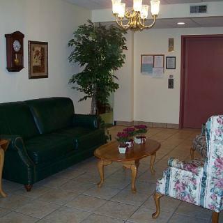 A cozy lobby area with a sofa, armchair, and table near an elevator.