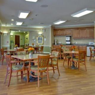 A spacious dining area with wooden tables and chairs, adjacent to a kitchen.