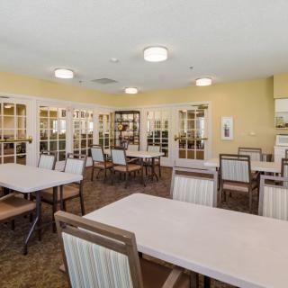 A community dining room with tables and chairs arranged neatly, illuminated by overhead lighting.