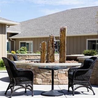 An outdoor patio area featuring a round table with wicker chairs and a decorative fountain centerpiece.