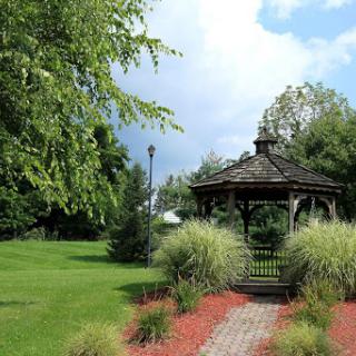 A serene garden featuring a charming gazebo surrounded by lush greenery and a well-maintained pathway.