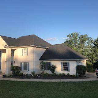 A modern two-story house basking in the sunlight, surrounded by a well-maintained lawn.