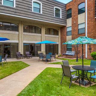 A cozy courtyard with outdoor seating and umbrellas at the back of a building.