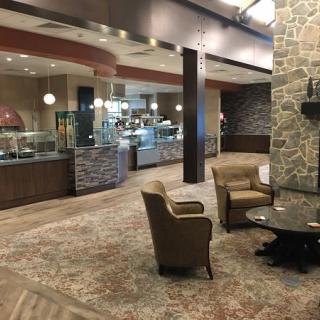 A modern lounge area with comfortable seating and a stone accent wall, adjacent to a cafe-style dining space.