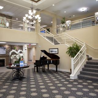 A spacious hotel lobby featuring a grand piano and an elegant staircase.