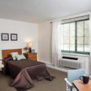 A cozy bedroom with a bed, dresser, and large window.