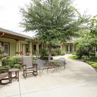 A serene outdoor garden area with chairs and a winding pathway surrounded by trees.