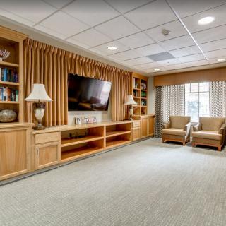 A cozy living room with a large television, built-in bookshelves, and comfortable armchairs.