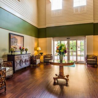 A brightly lit hotel lobby with elegant decor and a central round table adorned with fresh flowers.