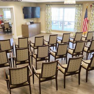 An indoor meeting space with arranged chairs facing a television and an American flag.