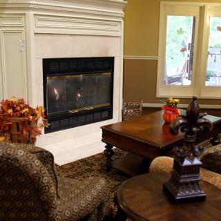 A cozy living room with a fireplace, comfortable chairs, and a wooden table, creating an inviting atmosphere.