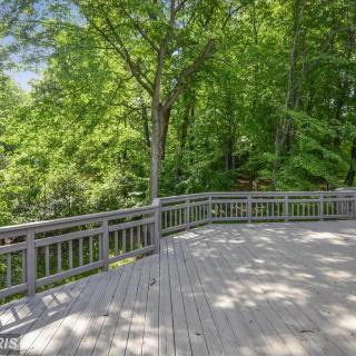 A spacious wooden deck overlooking a lush forest.