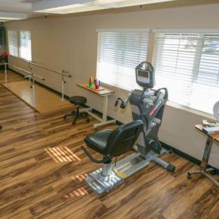 A therapy room equipped with exercise machines and parallel bars.
