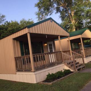 A quaint wooden cabin with a front porch set amidst trees.