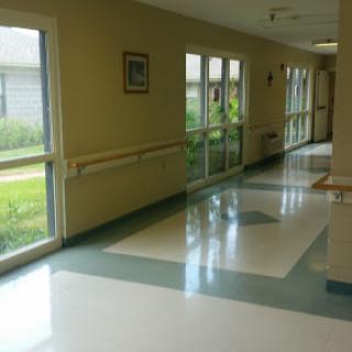 A well-lit hallway in a facility featuring large windows and clean flooring.