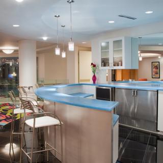 A modern kitchen with sleek design, featuring a blue countertop and bar stools.